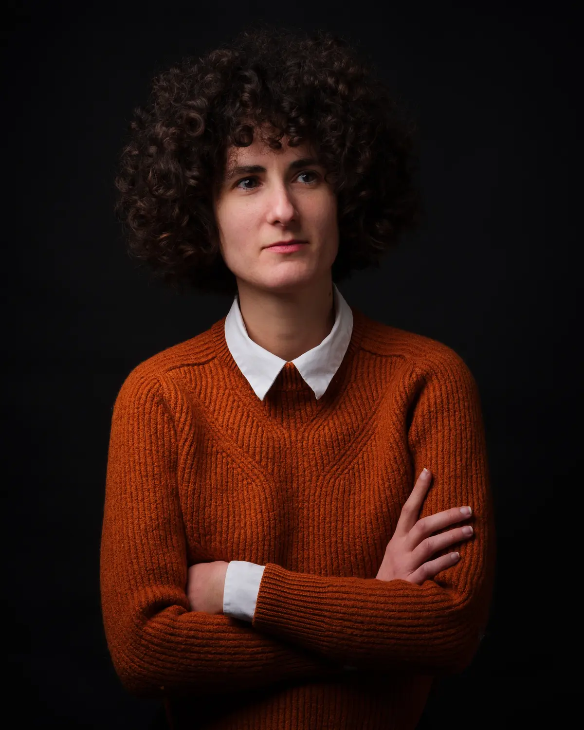 Portrait d'une personne en pull orange, bras croisés, studio — BLH Photographie